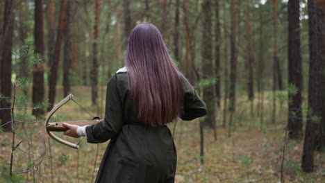 Teenage-girl-with-crossbow-walks-to-hunt-in-wild-forest