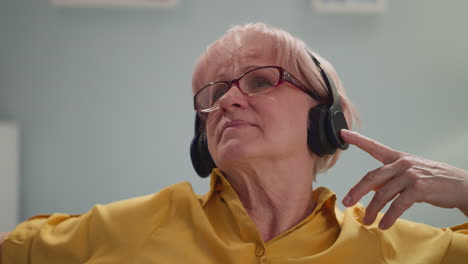 Senior-woman-listens-to-music-via-headphones-at-home