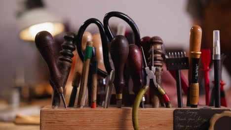 Rack-with-kit-of-different-leathersmith-tools-on-workbench