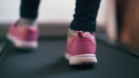 girl-feet-in-pink-sneakers-walk-on-treadmill-close-view