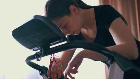 brunette-woman-rests-after-training-on-treadmill-near-window