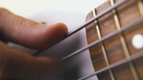 person-tries-backbeat-technique-on-white-bass-guitar-closeup