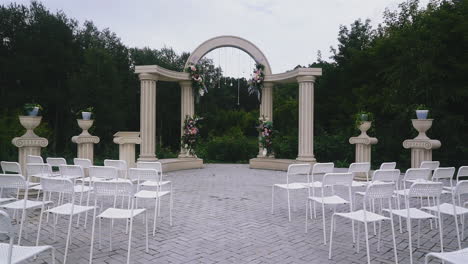 wedding-venue-with-empty-chairs-and-antique-arch-near-trees