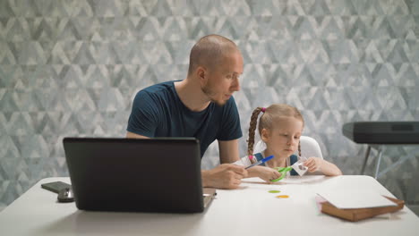 pretty-girl-cuts-out-paper-while-father-looks-at-daughter