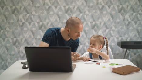 father-helps-daughter-to-unglue-sticker-sitting-at-table