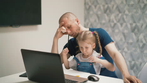tired-father-sits-at-table-with-girl-drawing-computer-mouse