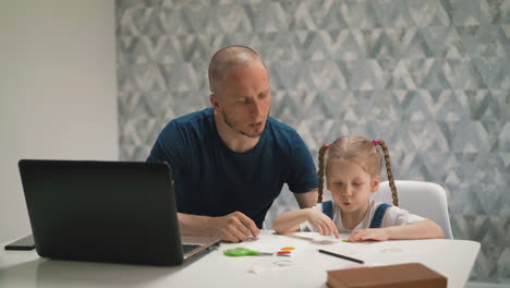 father-helps-daughter-glue-colorful-sticker-on-paper