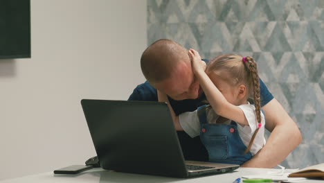 Kleines-Mädchen-Schüttelt-Den-Kopf-Des-Vaters-Und-Hat-Spaß-In-Der-Nähe-Eines-Modernen-Laptops