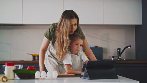 woman-with-daughter-watches-cooking-recipes-with-tablet