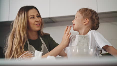 mother-cleans-little-daughter-chin-cooking-together-at-table