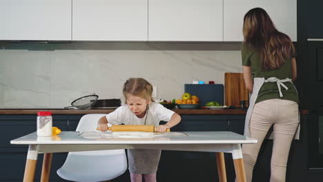 daughter-rolls-dough-with-pin-cooking-together-with-mother