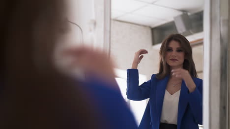 Positive-woman-with-makeup-adjusts-hair-looking-in-mirror