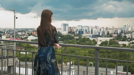 Lady-leans-on-handrail-on-viewing-deck-against-large-city