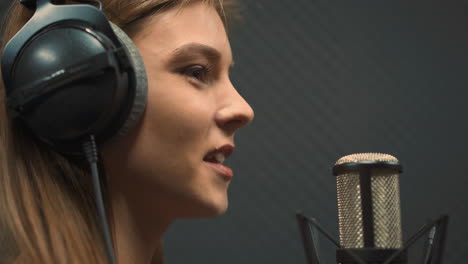 Pretty-woman-with-headphones-sings-song-with-microphone
