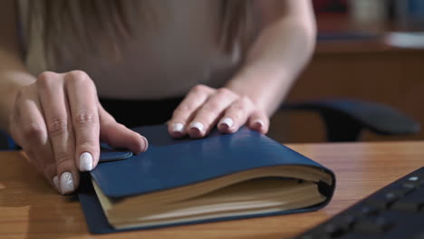 Young-businesswoman-in-blouse-sits-down-and-opens-notebook