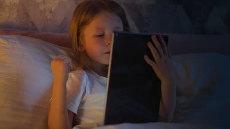 Joyful-child-happy-of-winning-in-videogame-on-tablet-on-bed