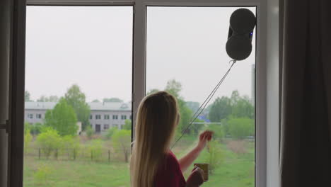 Woman-with-cup-taps-on-glass-robot-cleaner-washes-window