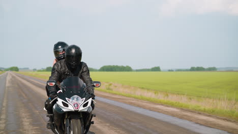 Motorcyclist-with-girlfriend-rides-motorbike-at-rural-site