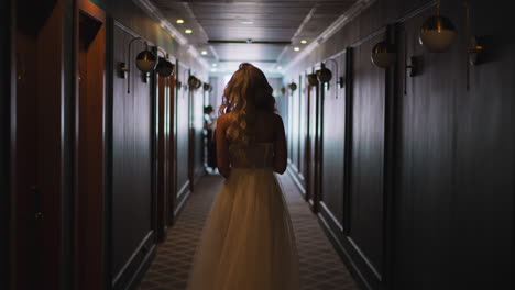 Graceful-woman-in-white-wedding-dress-walks-along-hallway