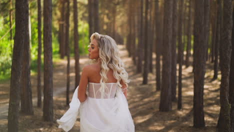 Pretty-woman-bride-with-flying-curly-hair-runs-along-forest