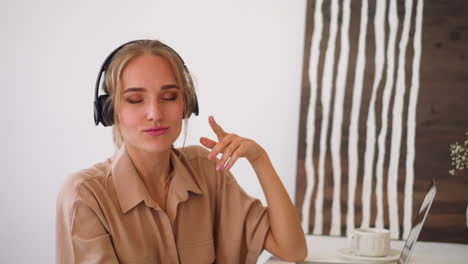 Woman-listens-to-music-in-headphones-while-working-at-laptop