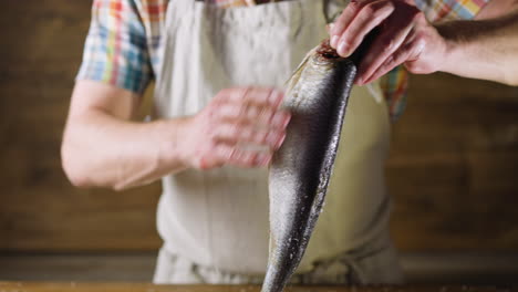 Man-in-apron-removes-salt-from-tasty-fat-marinated-herring