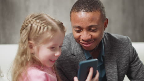 Little-child-and-carer-man-watch-educative-content-via-phone