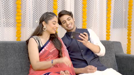 Glückliches-Indisches-Paar,-Das-Etwas-Am-Telefon-Beobachtet