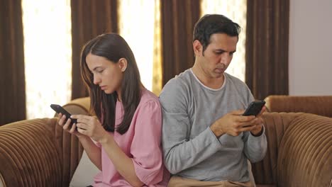 Indischer-Ehemann-Und-Ehefrau-Sind-Mit-Ihren-Mobiltelefonen-Beschäftigt