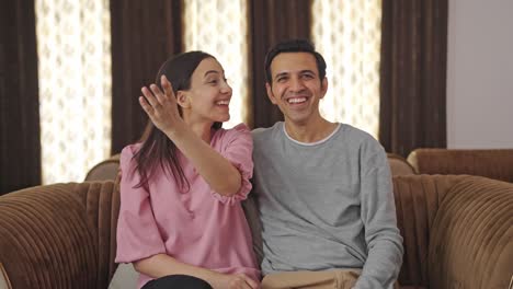 Happy-Indian-couple-watching-TV-and-laughing