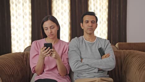 Indian-husband-watching-TV-and-wife-using-mobile-phone