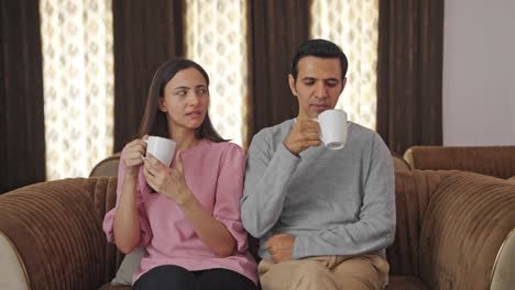 Annoyed-Indian-couple-drinking-tea-and-talking