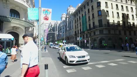 Gran-Bulevar-De-Madrid-Con-Gente-Cruzando-La-Calle-Y-Coches