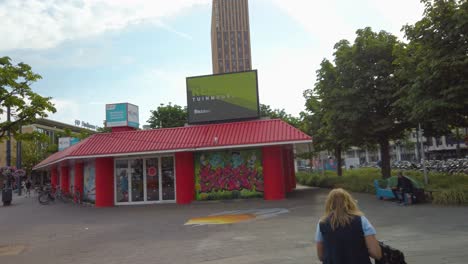 Frau-Steht-Vor-Einem-Geschäftsgebäude-Mit-Hotelturm-Im-Hintergrund-In-Eindhoven,-Niederlande
