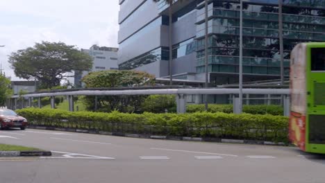 Green-Public-Double-decker-Bus-Followed-By-A-Car-Turning-Left-At-The-Junction-In-Changi-Business-Park-In-Singapore