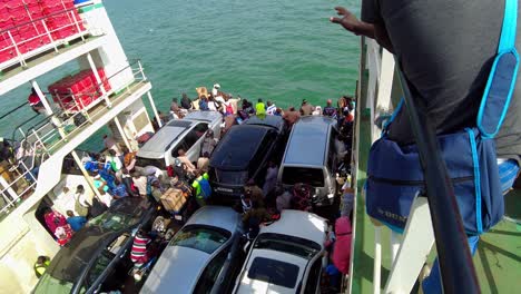 Vista-De-Pájaro-Inclinada-Hacia-Abajo-De-Personas-Y-Vehículos-Dentro-Del-Ferry-Kunta-Kinteh-Que-Navega-Desde-Banjul-A-Barra---Gambia,-África-Occidental