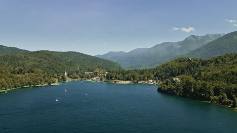 Drone-aerial-flyover-above-scenic-Lake-Bohinj-Slovenia-midday,-blue-sky
