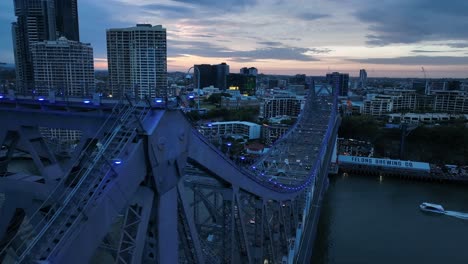 Close-up-aerial-flyover-shot-of-Story-Bridge,-camera-narrowly-passes-top-of-bridge,-pans-down-revealing-bridge-structure-and-traffic-below