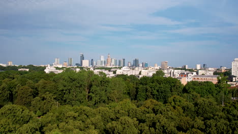 Aerial-Panorama-of-Warsaw-Downtown-Cityscape-in-Backdrop-of-Lush-Green-Forest-on-Sunny-Summer-Day
