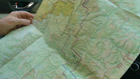 Closeup-of-elderly-hands-holding-hiking-map,-car-interior