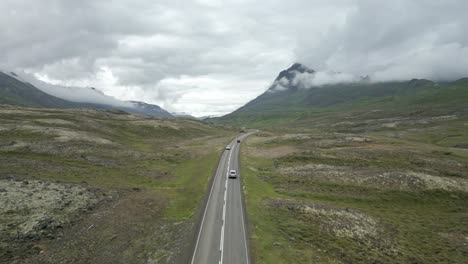 Viaje-Tranquilo-Por-El-Campo-Islandés-Bajo-Los-Picos-De-Las-Montañas-Brumosas,-Disparo-Aéreo-De-Drones