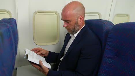 A-man-with-a-beard-reading-a-book-flying-on-a-passenger-plane-airliner