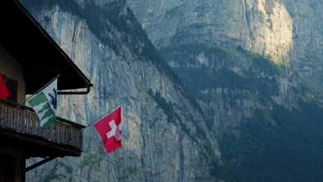 Lauterbrunnen-rock-wall-and-balcony-of-wooden-mountain-village-chalet-with-Swiss-flag