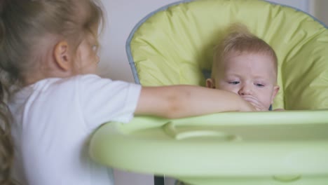girl-takes-off-bottle-from-junior-brother-in-soft-highchair