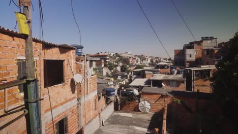 Wide-shot-showing-old-destroyed-Favela-housing-area-of-Sao-Paulo-with-cables-during-sunny-day-and-blue-sky,-Brazil