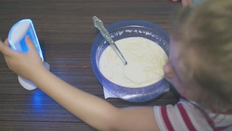 girl-eats-milk-pasta-playing-with-baby-monitor-at-table