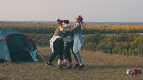 happy-girls-hug-and-spin-near-tent-and-campfire-in-autumn