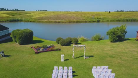 wedding-venue-with-arch-and-chairs-near-river-upper-view