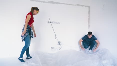 couple-covers-floor-with-foil-near-white-wall-in-own-house