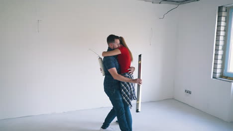 woman-with-spray-foam-hugs-boyfriend-with-level-in-room